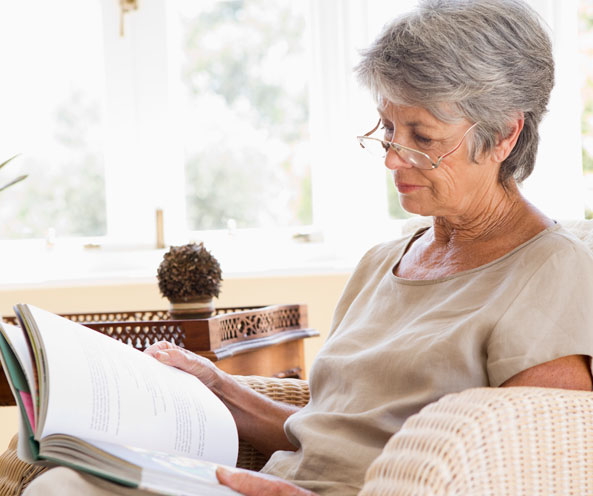 Elderly woman reading in lounge.