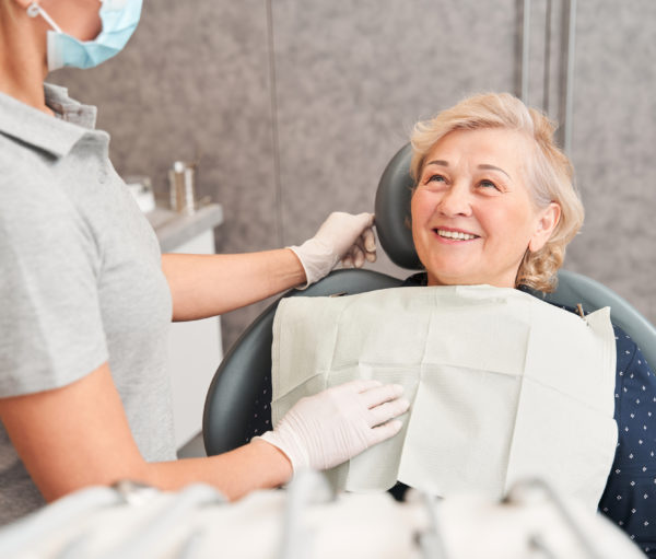 Woman sitting in dental chair and listening to dentist